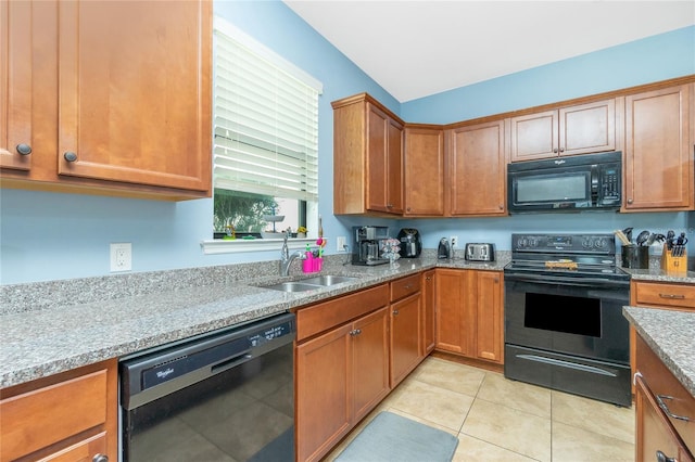 kitchen featuring black appliances, brown cabinetry, light tile patterned flooring, and a sink