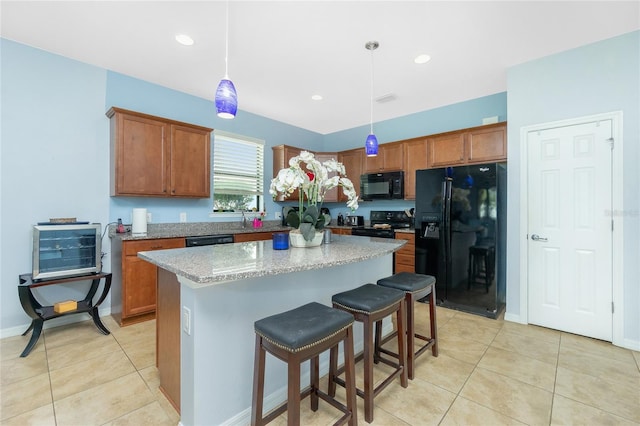 kitchen with light tile patterned floors, black appliances, a center island, and brown cabinets