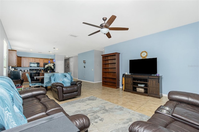 living room with light tile patterned floors, ceiling fan, and baseboards