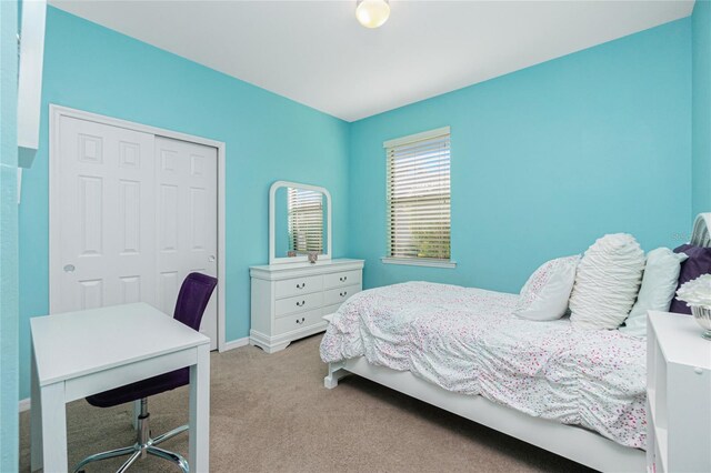 carpeted bedroom featuring baseboards and a closet