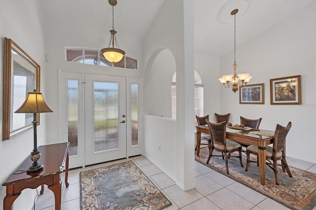 foyer entrance with high vaulted ceiling, arched walkways, a notable chandelier, and light tile patterned floors