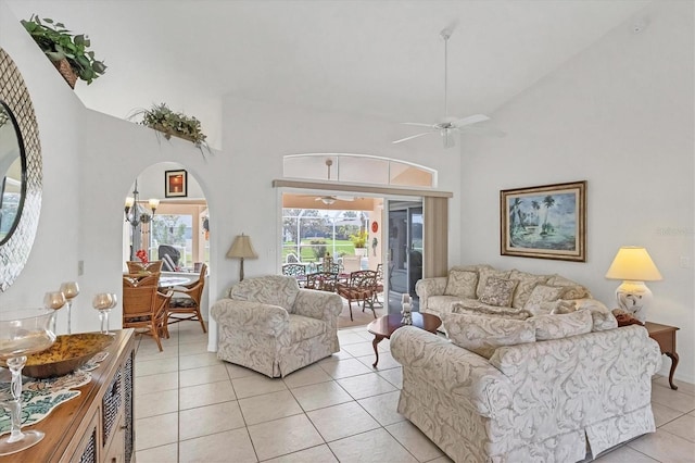 living area featuring a towering ceiling, ceiling fan, arched walkways, and light tile patterned flooring