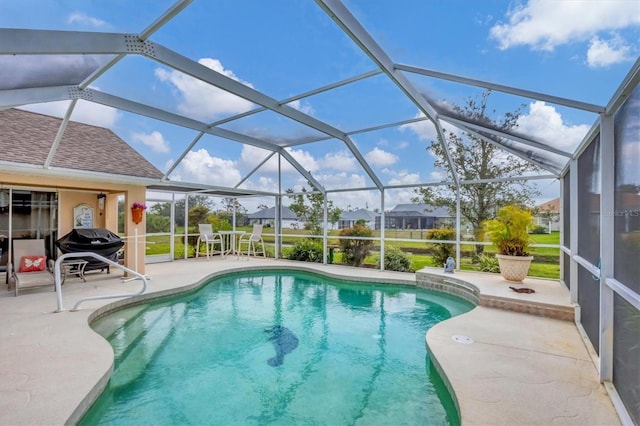 outdoor pool featuring glass enclosure, grilling area, and a patio