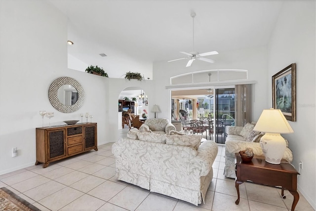 living area featuring arched walkways, a towering ceiling, and light tile patterned floors