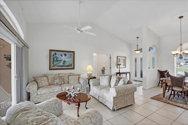 living area with ceiling fan with notable chandelier, high vaulted ceiling, and light tile patterned flooring