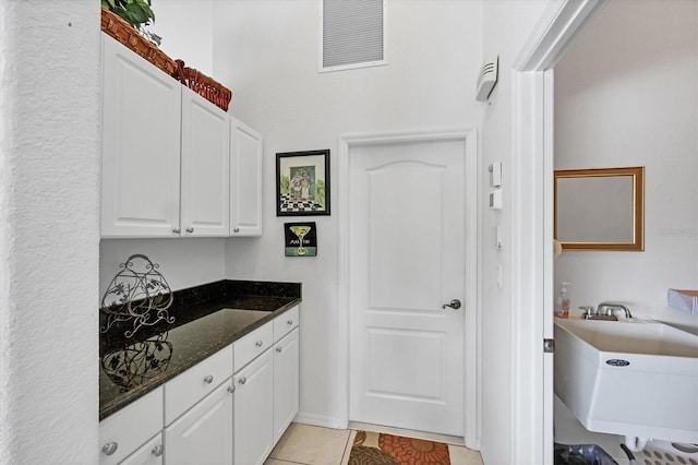 kitchen with white cabinets, visible vents, dark stone countertops, and light tile patterned floors