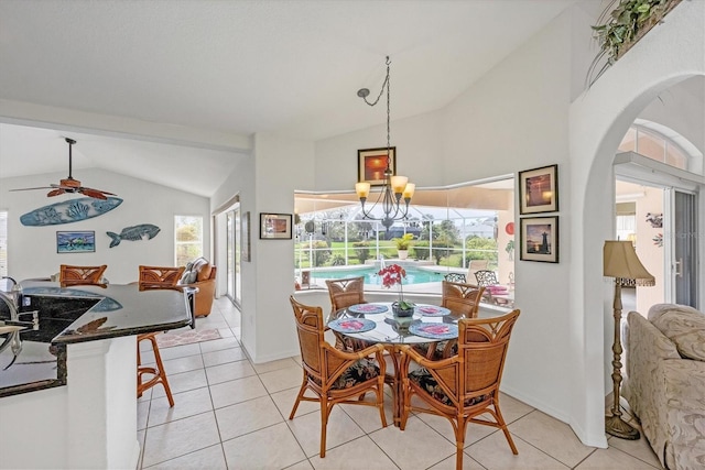 dining area featuring ceiling fan with notable chandelier, lofted ceiling, arched walkways, and light tile patterned floors