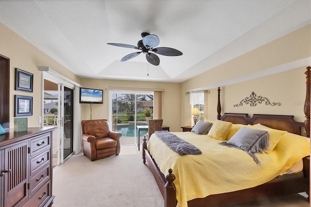 bedroom featuring access to exterior, ceiling fan, a tray ceiling, and light colored carpet