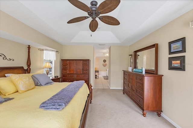 bedroom featuring baseboards, ensuite bath, a raised ceiling, and light colored carpet