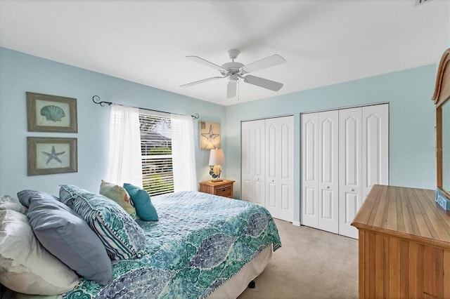 bedroom featuring multiple closets, light colored carpet, and ceiling fan