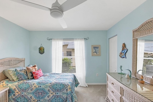 bedroom featuring a ceiling fan, light carpet, baseboards, and multiple windows