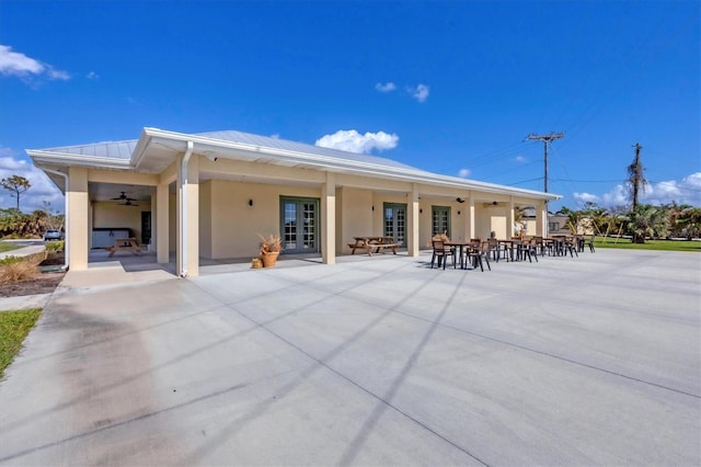 rear view of property featuring stucco siding, a patio area, metal roof, and french doors