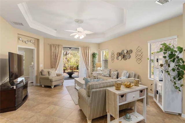 living area with a ceiling fan, a tray ceiling, and visible vents