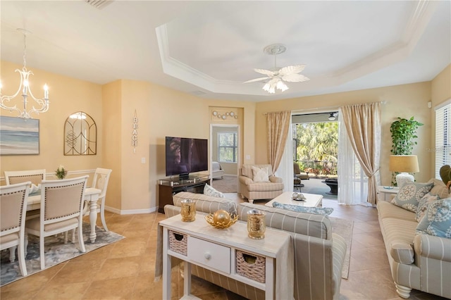 living area featuring ceiling fan with notable chandelier, a tray ceiling, light tile patterned flooring, and baseboards