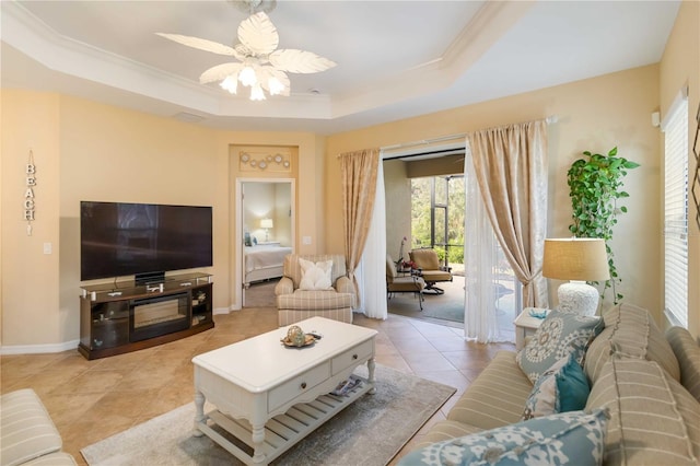 living room with a raised ceiling, ornamental molding, light tile patterned flooring, ceiling fan, and baseboards