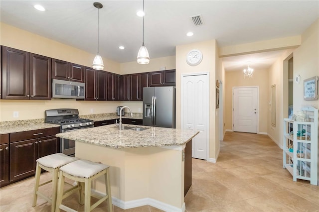 kitchen with stainless steel appliances, a sink, visible vents, dark brown cabinets, and a center island with sink