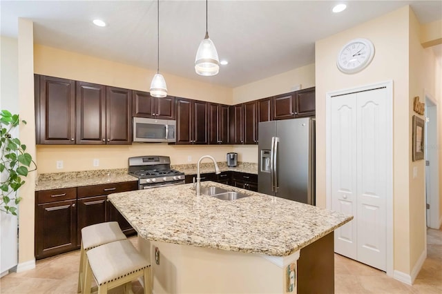 kitchen featuring dark brown cabinets, appliances with stainless steel finishes, a sink, and light stone counters