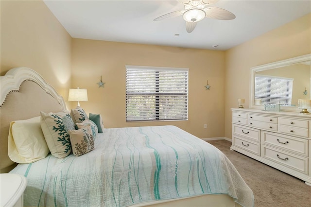 bedroom featuring light carpet, ceiling fan, baseboards, and multiple windows