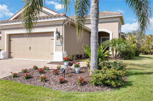 view of front of property featuring an attached garage, a tiled roof, decorative driveway, stucco siding, and a front yard