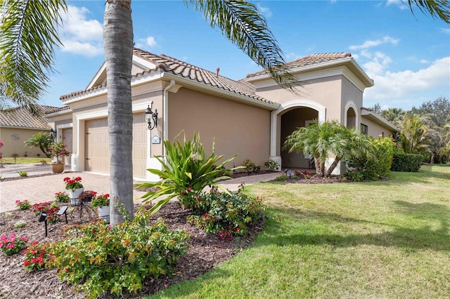 mediterranean / spanish-style home with a garage, a tiled roof, a front yard, and stucco siding