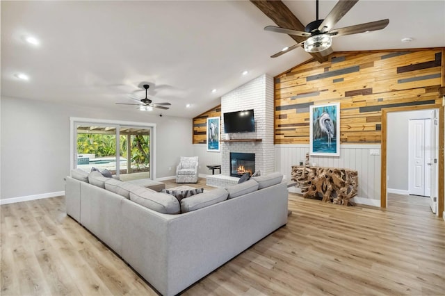 living area with ceiling fan, light wood-style flooring, wooden walls, and a fireplace