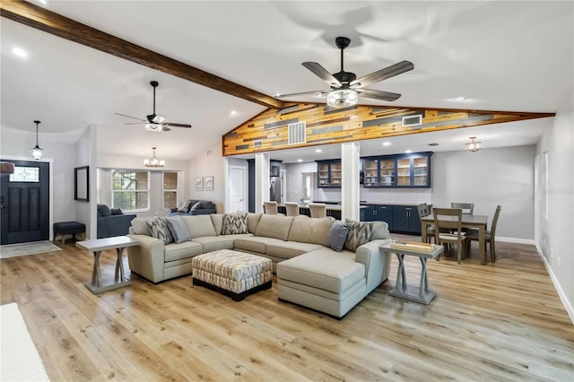 living room featuring visible vents, baseboards, lofted ceiling with beams, light wood-style floors, and ceiling fan with notable chandelier