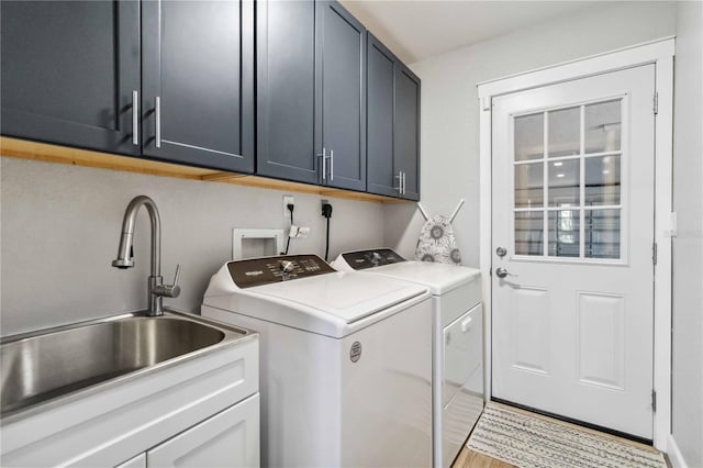 clothes washing area featuring washing machine and clothes dryer, a sink, and cabinet space