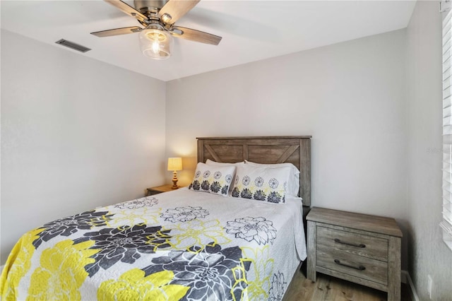 bedroom with ceiling fan, wood finished floors, and visible vents