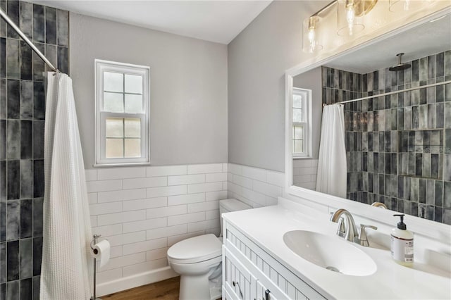 full bathroom featuring a tile shower, tile walls, toilet, and vanity