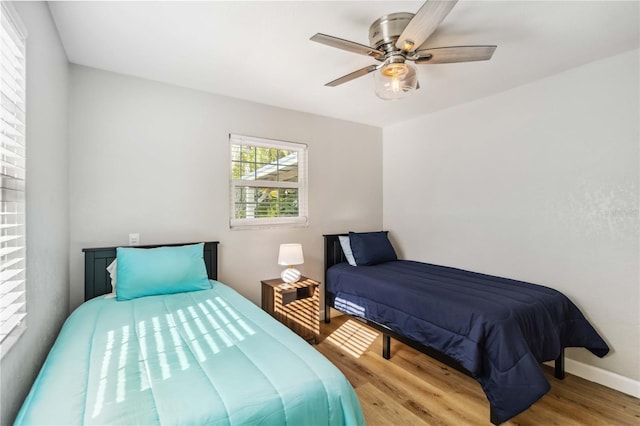 bedroom featuring wood finished floors, a ceiling fan, and baseboards