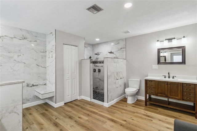 full bath with toilet, a marble finish shower, wood finished floors, and visible vents