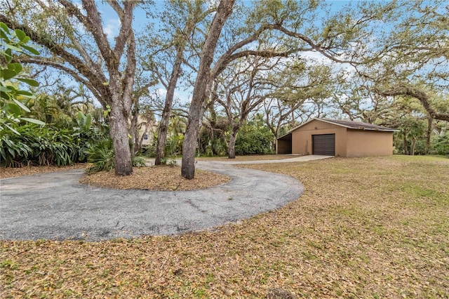 view of yard featuring an outbuilding, aphalt driveway, and a detached garage