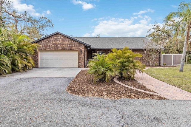 single story home with driveway, a garage, fence, a front lawn, and brick siding