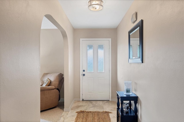 foyer entrance with baseboards and arched walkways