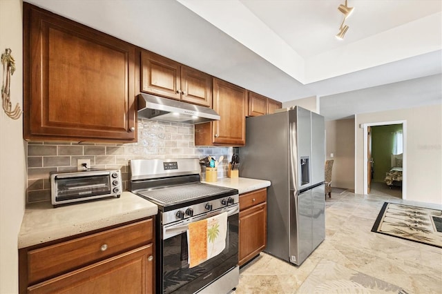 kitchen featuring a toaster, appliances with stainless steel finishes, light countertops, under cabinet range hood, and backsplash