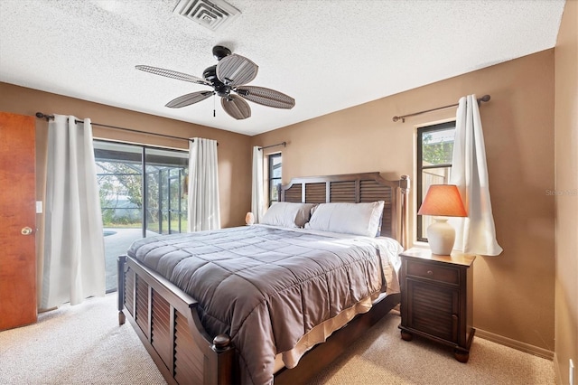 bedroom featuring access to exterior, light colored carpet, visible vents, a textured ceiling, and baseboards