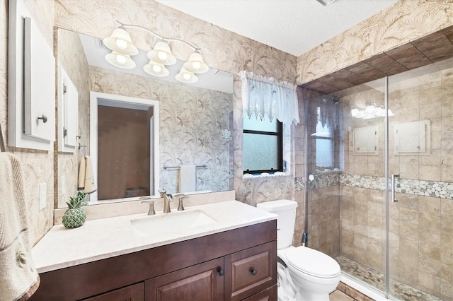 bathroom featuring toilet, wallpapered walls, a shower stall, and vanity