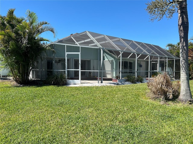 rear view of house with a yard and glass enclosure