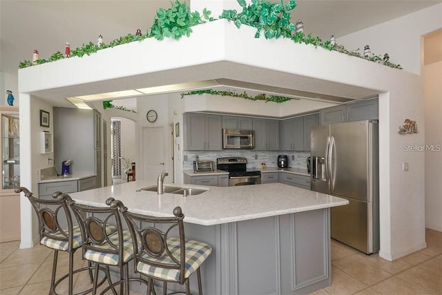kitchen with a sink, light tile patterned flooring, gray cabinets, and appliances with stainless steel finishes