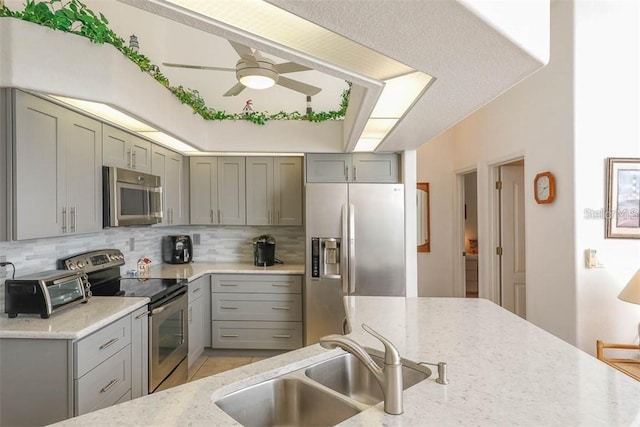 kitchen with gray cabinetry, tasteful backsplash, appliances with stainless steel finishes, and a sink