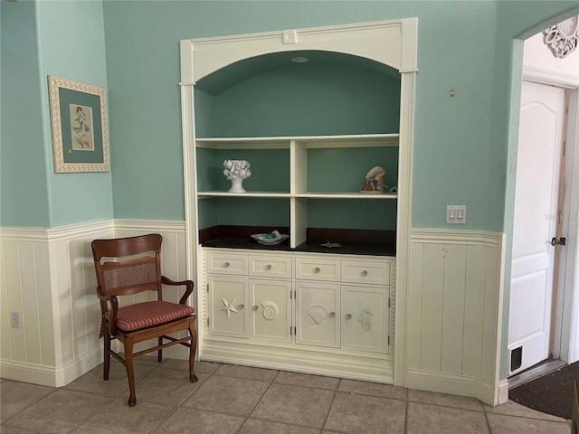 sitting room with wainscoting and light tile patterned floors