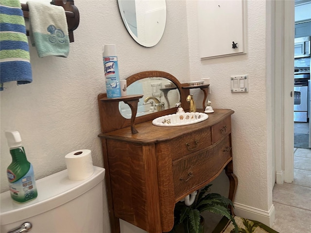 bathroom featuring toilet, vanity, and baseboards