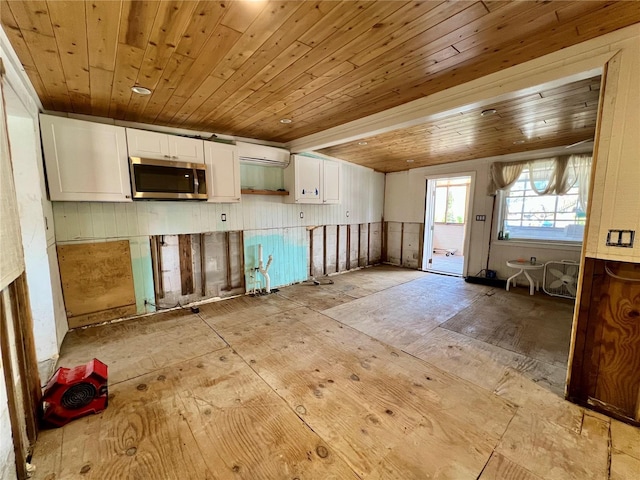 kitchen featuring white cabinets, stainless steel microwave, wooden ceiling, and an AC wall unit