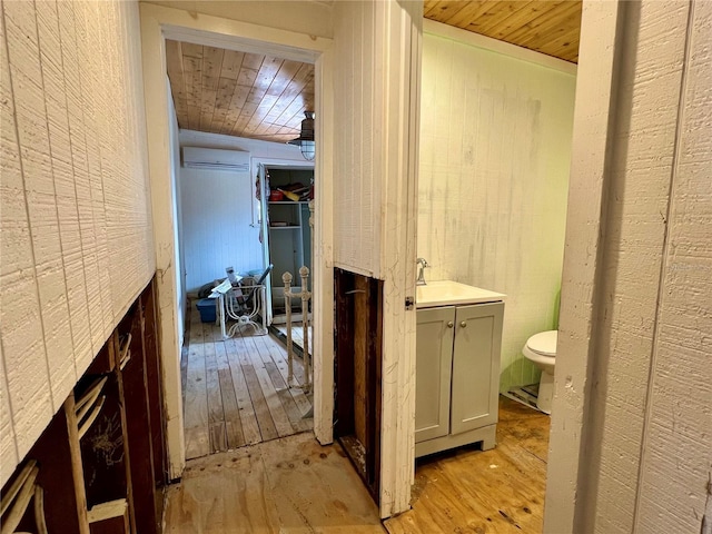 bathroom with vanity, a wall unit AC, wood-type flooring, and wood ceiling