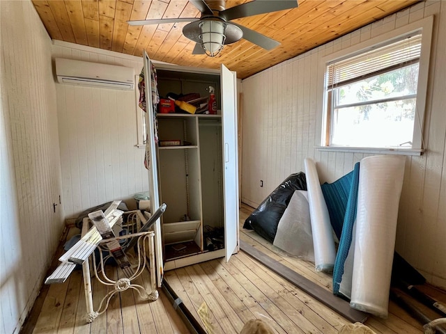 interior space with wooden ceiling, wood walls, a ceiling fan, a wall mounted AC, and wood-type flooring