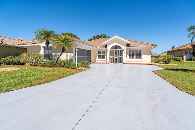 view of front of property featuring driveway, a tile roof, a front yard, and stucco siding