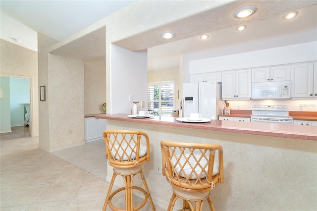 kitchen featuring light tile patterned floors, recessed lighting, light countertops, white cabinetry, and white appliances