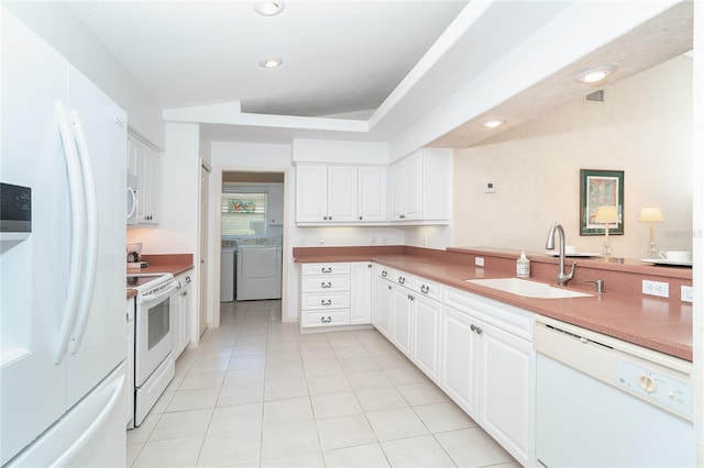 kitchen with white appliances, white cabinetry, washer and clothes dryer, and a sink