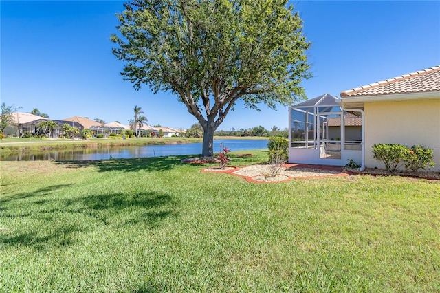 view of yard with a lanai and a water view