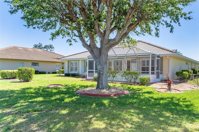 single story home with a front yard, glass enclosure, and a tiled roof